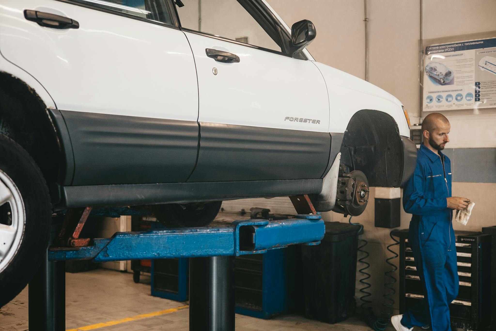 Mechanic evaluating a car on a lift for maintenance in an auto workshop.